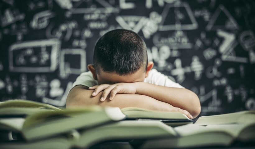 Um menino estudando e sonolento por cima de livros. Pisa: menos de 50% dos alunos sabem o básico em matemática e ciências
