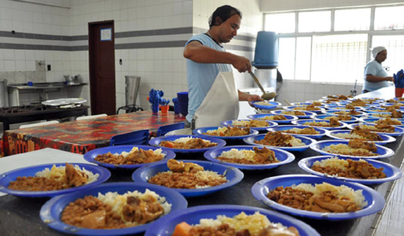 Funcionário preparando almoço escolar.