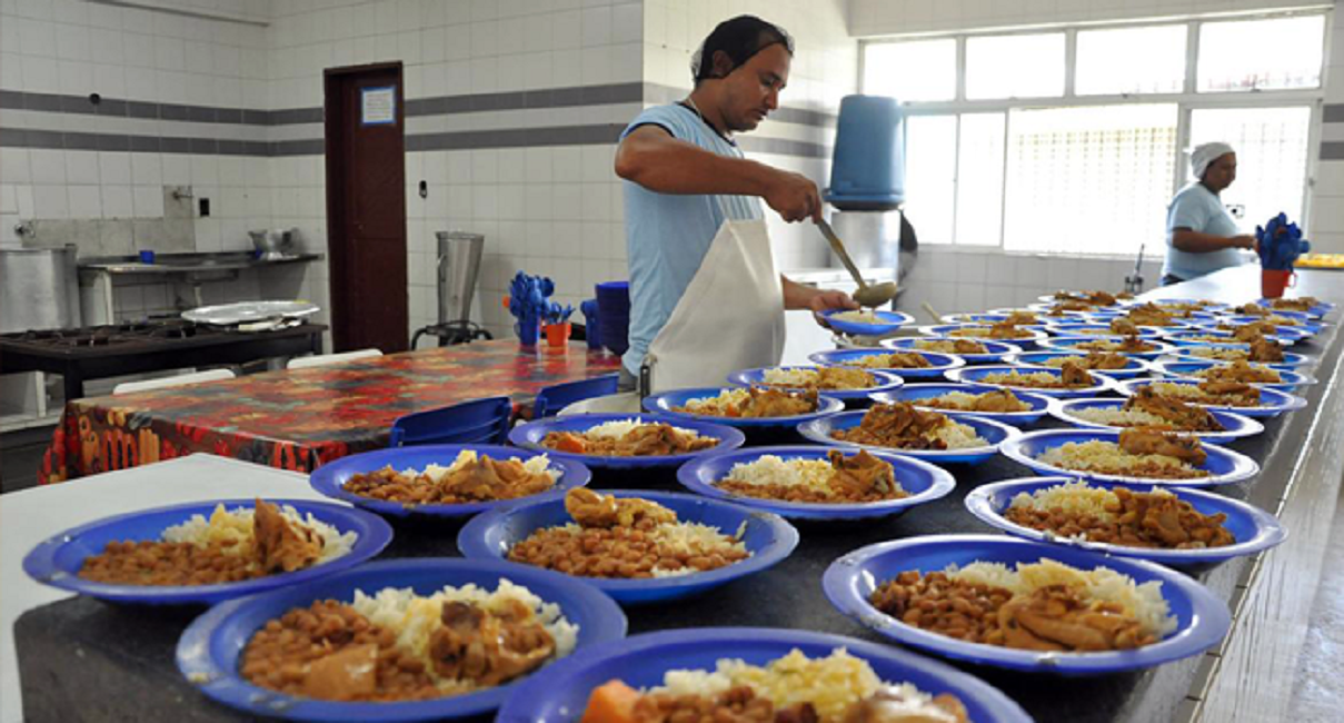 Funcionário preparando almoço escolar.