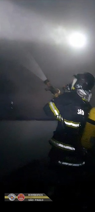 Bombeiro com mangueira para conter incêndio.