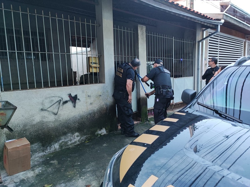 Policiais federais arrombando cadeado de portão de um suspeito.