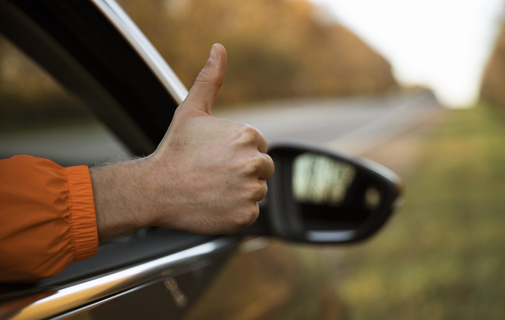 homem-fazendo-sinal-de-positivo-para-fora-do-carro-durante-uma-viagem. Prazo do IPVA 2024 dos veículos com placa final 7 vence nesta segunda-feira (19)