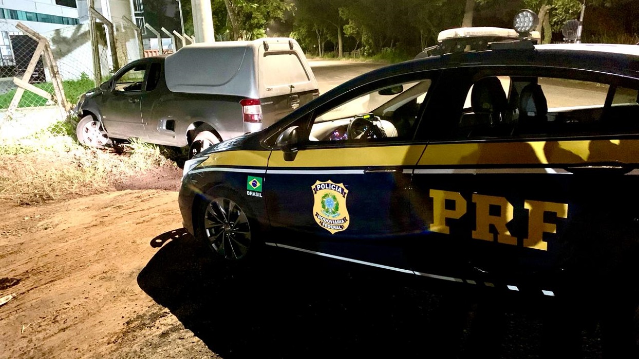Viatura da PRF próximo a veículo roubado que colidiu em muro, em Pinda. PRF recupera veículo roubado em Pindamonhangaba; um suspeito foi preso