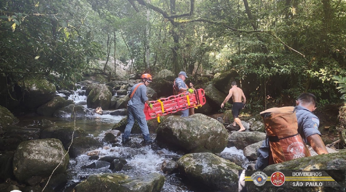 bombeiros caminhando sobre pedras próximos de cachoeira. Bombeiros resgatam vítima de acidente em cachoeira, em Caraguatatuba, SP