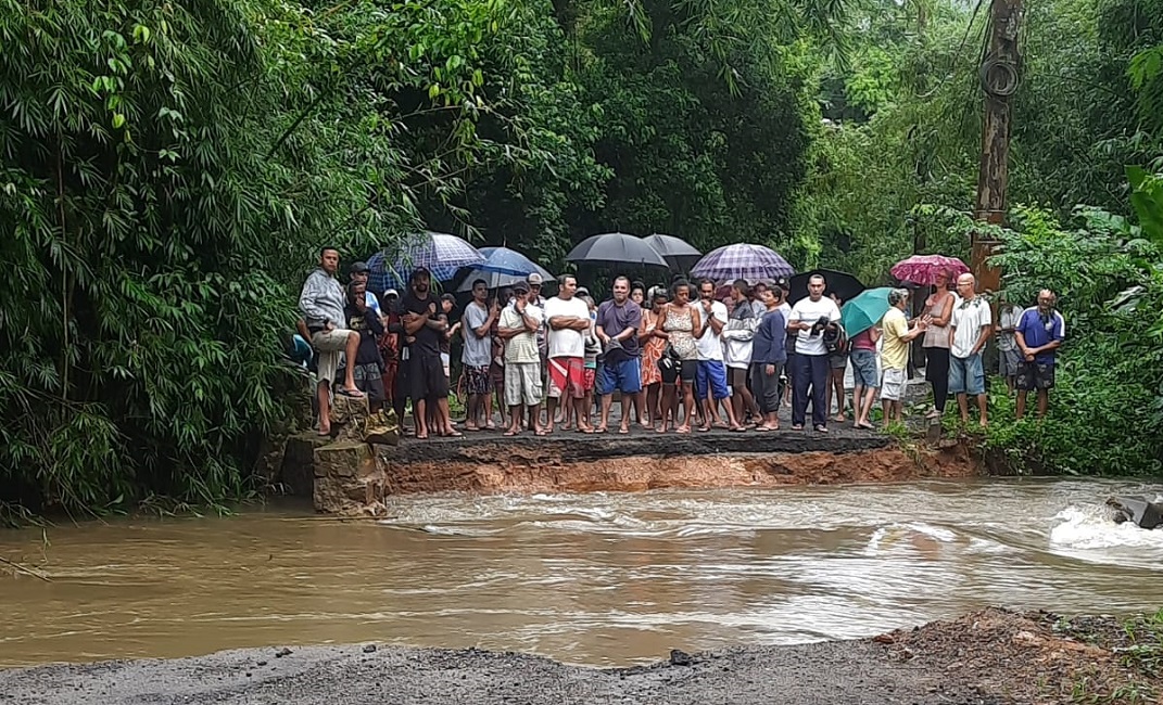 Pessoas isoladas em frente a rua alagada em Ubatuba