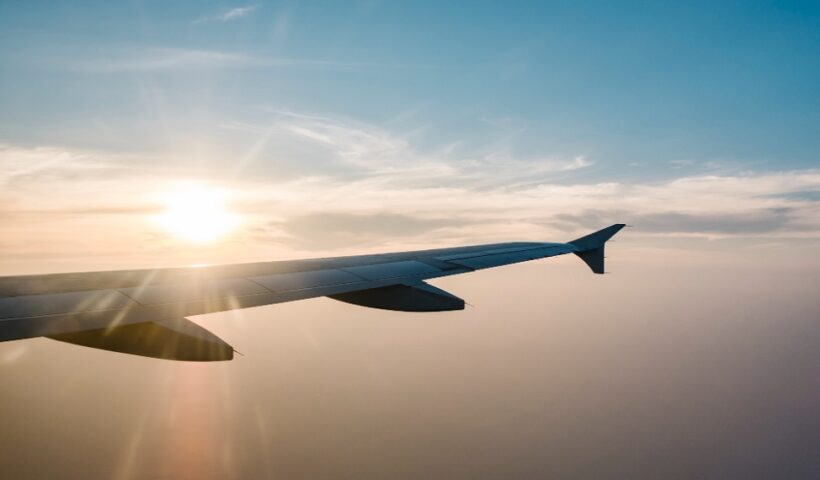 Parte lateral de um avião, na cor cinza, com um céu azul e iluminado ao fundo, ilustrando a matéria sobre vagas de emprego para o setor aeronáutico, no PAT de Taubaté.