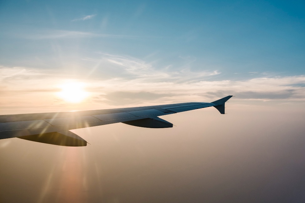 Parte lateral de um avião, na cor cinza, com um céu azul e iluminado ao fundo, ilustrando a matéria sobre vagas de emprego para o setor aeronáutico, no PAT de Taubaté.