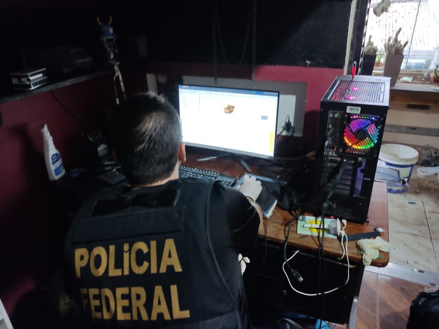 Policial federal de costas olha vídeos contendo exploração sexual infantojuvenil, em Taubaté