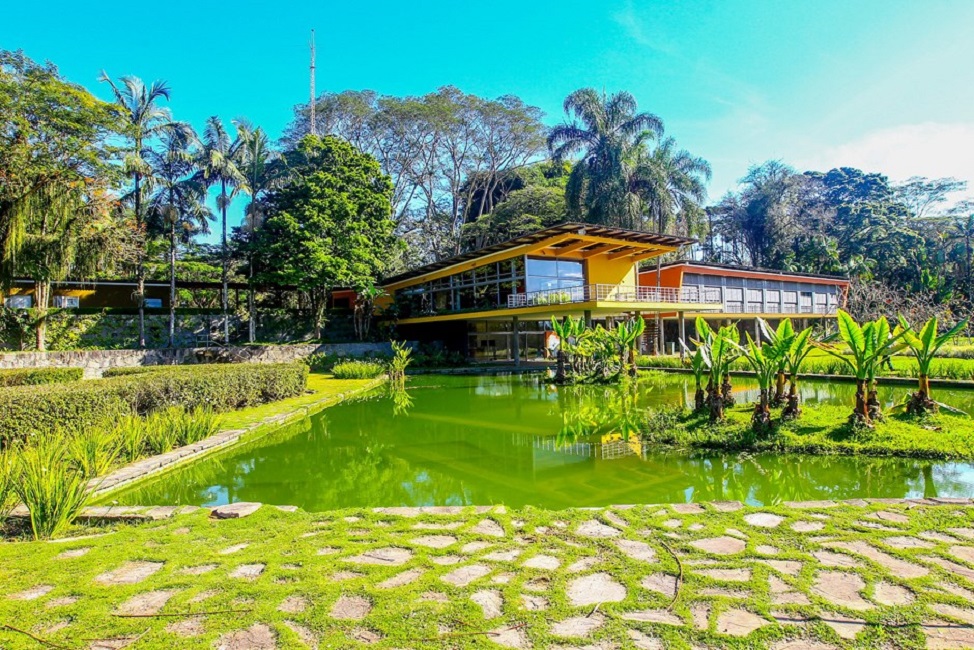Casa no Parque da Cidade de São José dos campos, localizada em meio à uma área verde, com um lago na frente e árvores ao fundo.