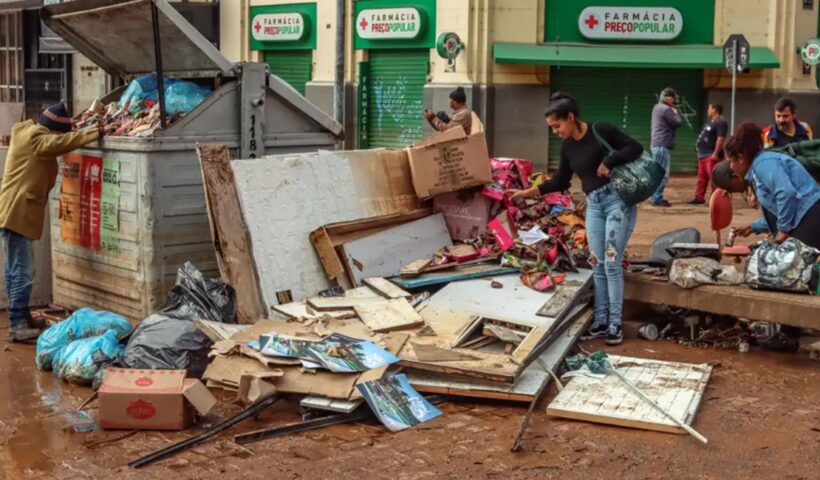 pessoas ao lado de destroços provocados por chuva no RS. Sobe para 161 número de mortes por chuvas no Rio Grande do Sul