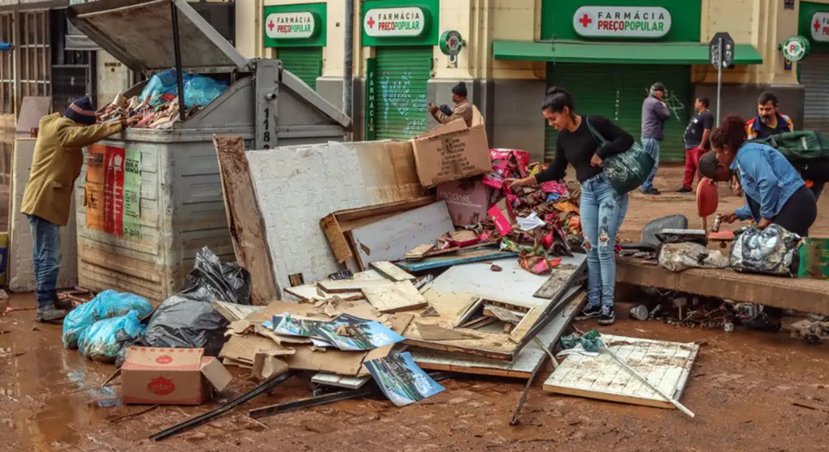 pessoas ao lado de destroços provocados por chuva no RS. Sobe para 161 número de mortes por chuvas no Rio Grande do Sul
