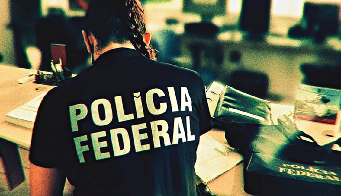 Policial federal de costas apurando documentos. PF desarticula esquema de fraudes tributárias em Campos do Jordão