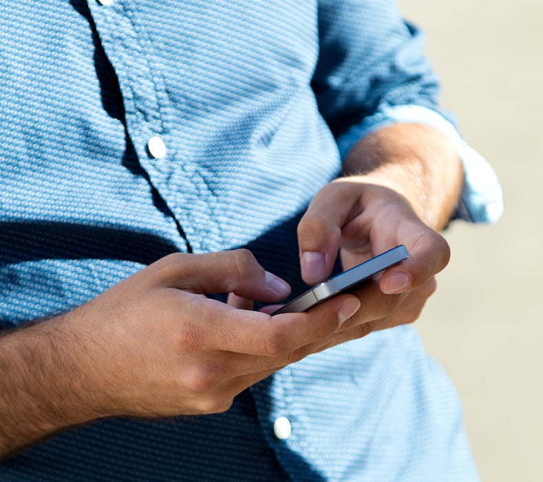 Young man using mobile phone in the street. -Homem é preso por extorquir homossexuais em aplicativo de encontros em São José