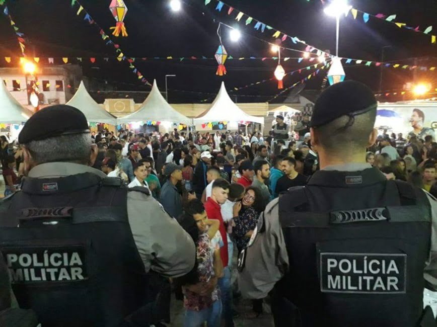 dois policiais de costas olhando festa de são joão. Homem em ‘saidinha temporária’ é detido em Festa de São João de Caçapava