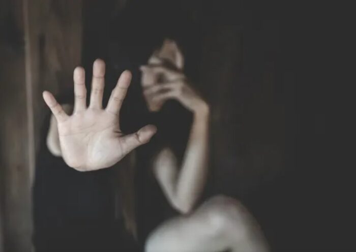 mulher em quarto escuro estica a palma da mão. Homem é preso por violência doméstica e ameaça em Piquete
