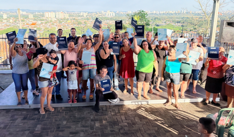 Diversas famílias felizes sorrindo para câmera levantando escrituras para alto