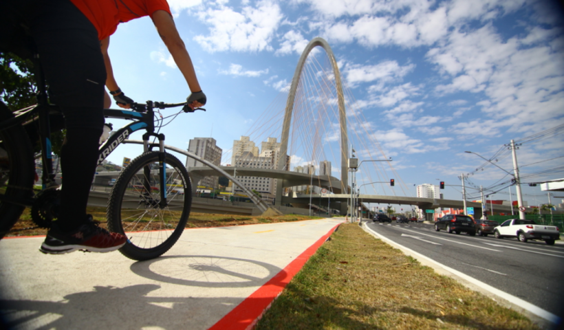 Pessoa andando de bicicleta próximo ao Arco da Inovação em São José dos Campos, na ciclovia