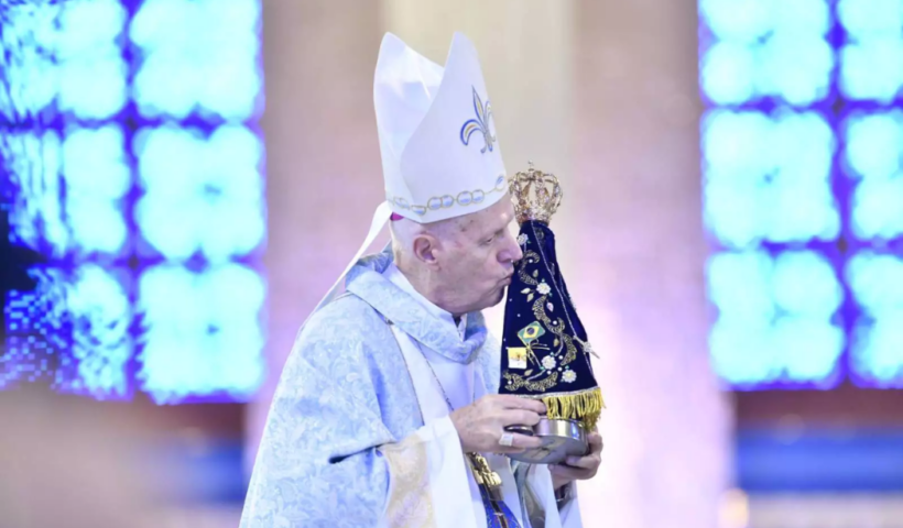 Dom Orlando Brandes, arcebispo de Aparecida, aparece vestindo paramentos litúrgicos brancos e beija com devoção a imagem original de Nossa Senhora Aparecida durante uma celebração religiosa