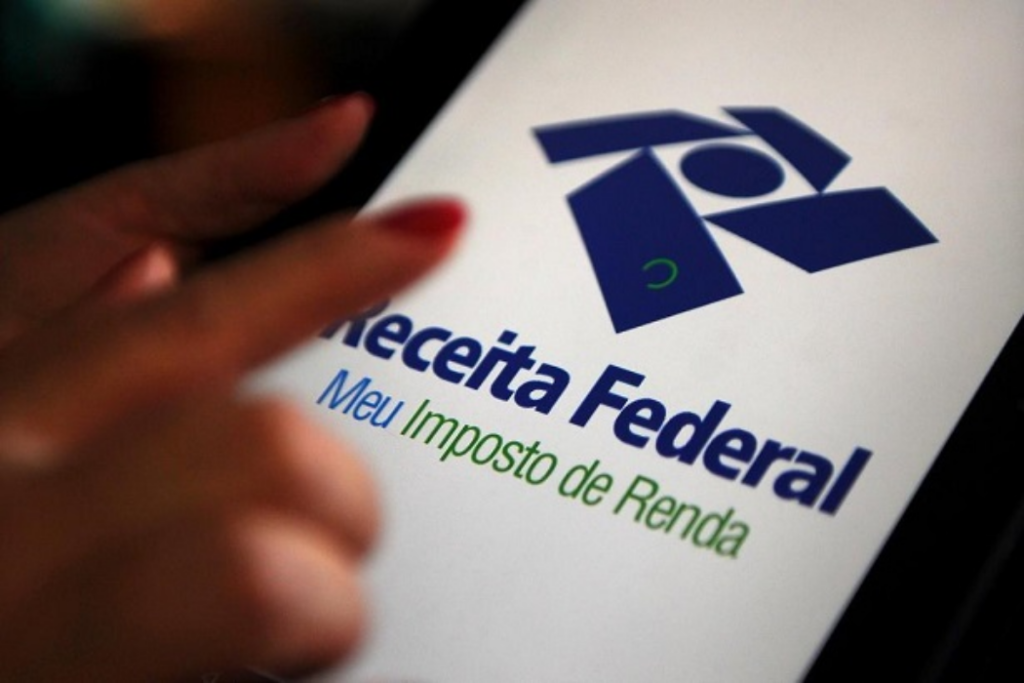 Dedo tocando celular com aplicativo da Receita Federal na tela