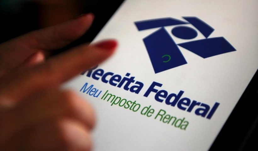 Dedo tocando celular com aplicativo da Receita Federal na tela