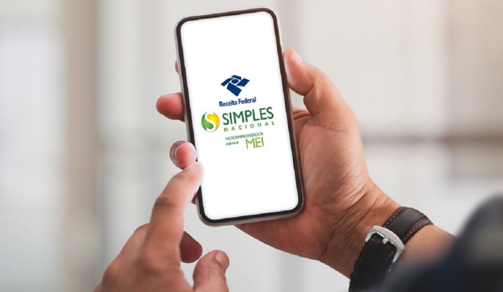 mãos de homem desugrando celular com app do MEI na tela