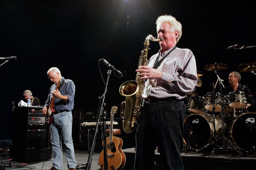 Dick Parry, saxofonista do Pink Floyd, tocando em palco com david gilmour ao fundo