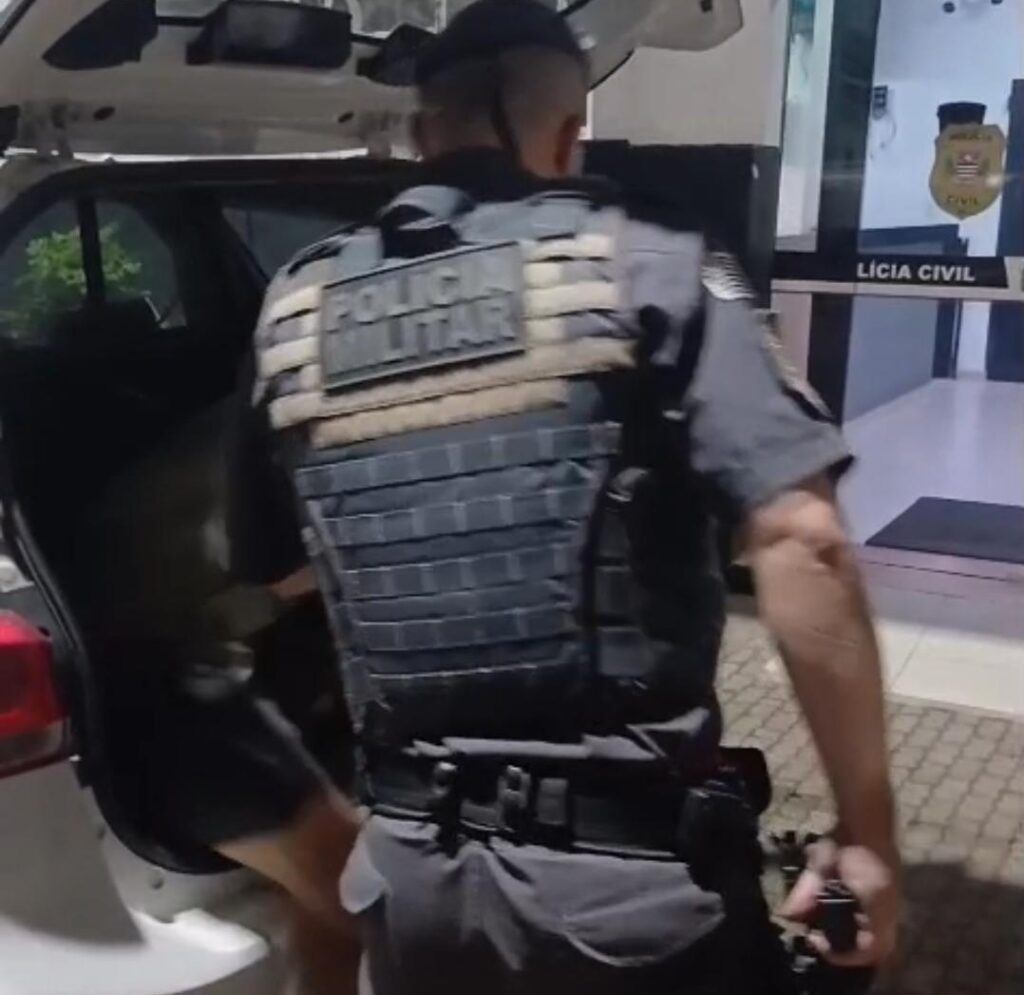 policial militar de costas retira suspeito de homicídio da parte de trás de viatura policial; tentou matar a mulher a facadas