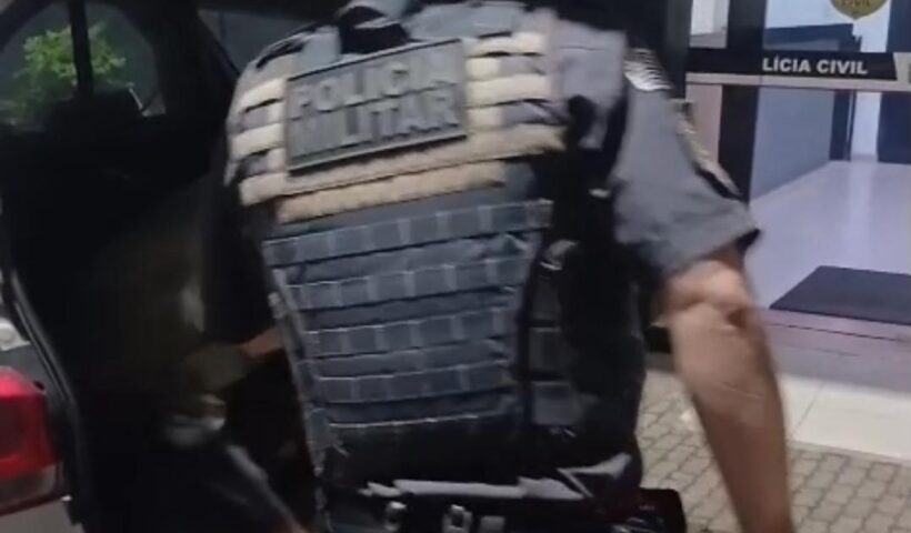 policial militar de costas retira suspeito de homicídio da parte de trás de viatura policial; tentou matar a mulher a facadas