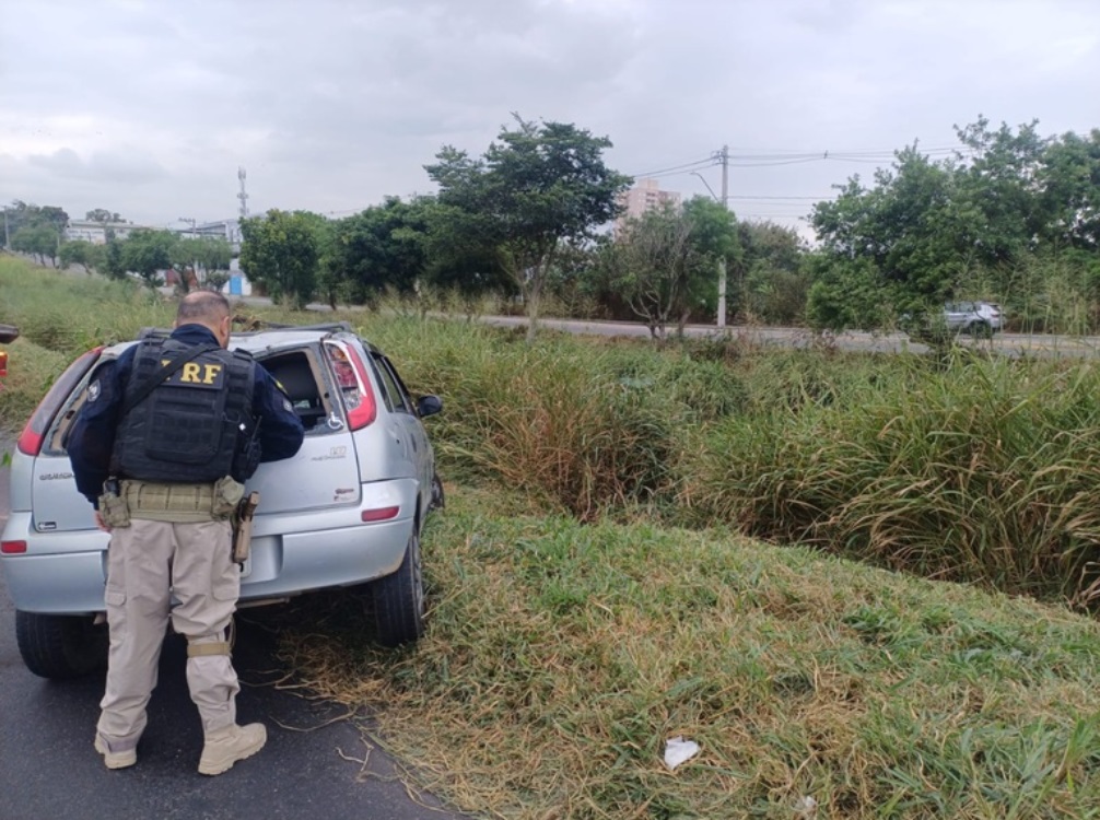 policial rodoviário verifica estado de veículo capotado na via dutra