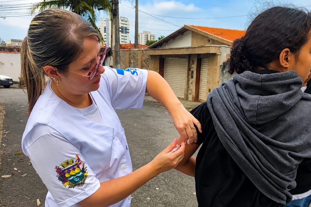 agente de saúde vacinando adolescente contra a dengue