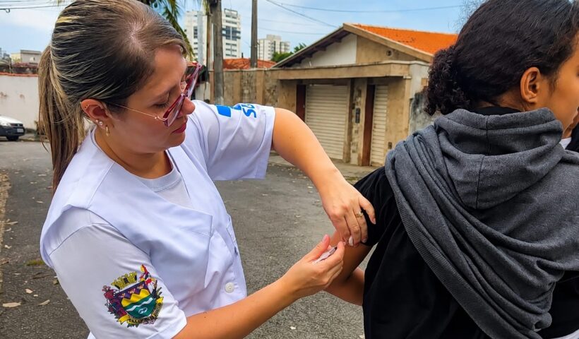 agente de saúde vacinando adolescente contra a dengue