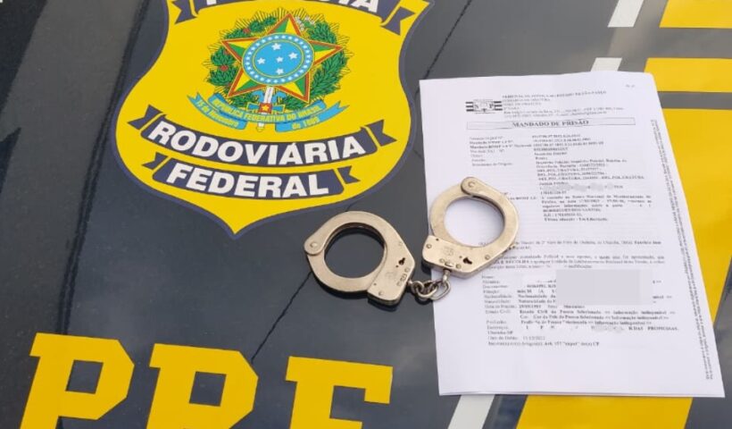 algemas e mandado de prisão por cima de capô de carro da PRF