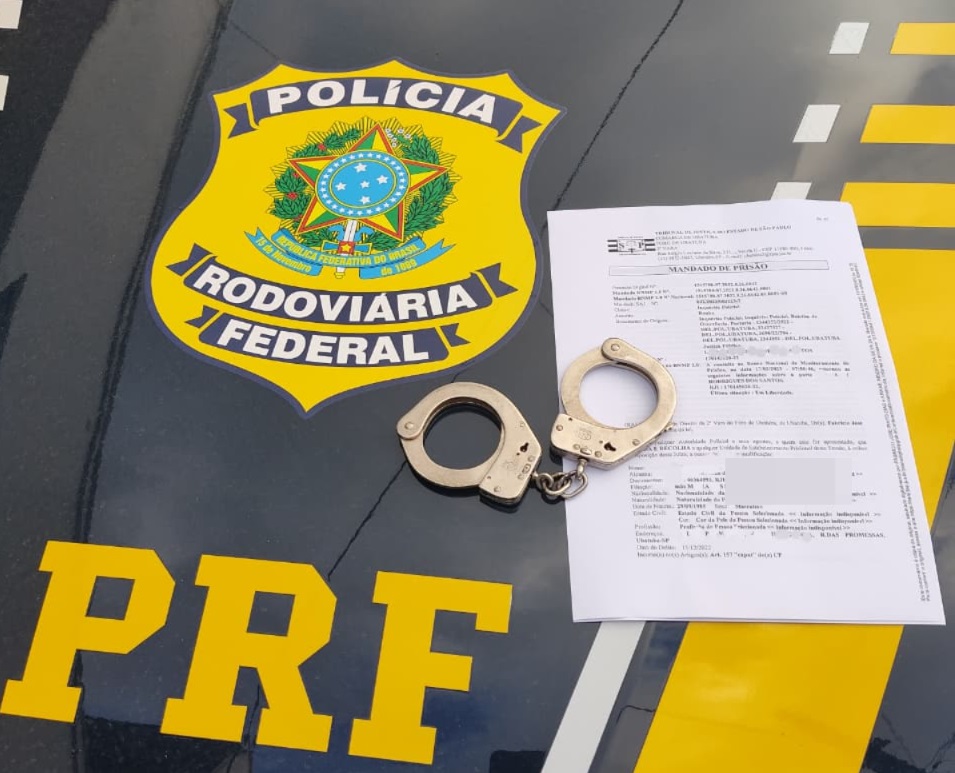 algemas e mandado de prisão por cima de capô de carro da PRF