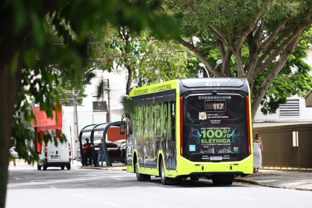 Ônibus do transporte público de São José dos Campos em uma rua cheia de árvores