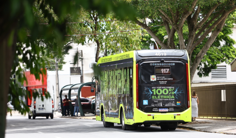Ônibus do transporte público de São José dos Campos em uma rua cheia de árvores