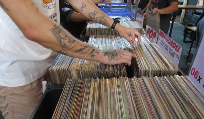 homem manuseando caixa com vinis ou PLs em feira de disco