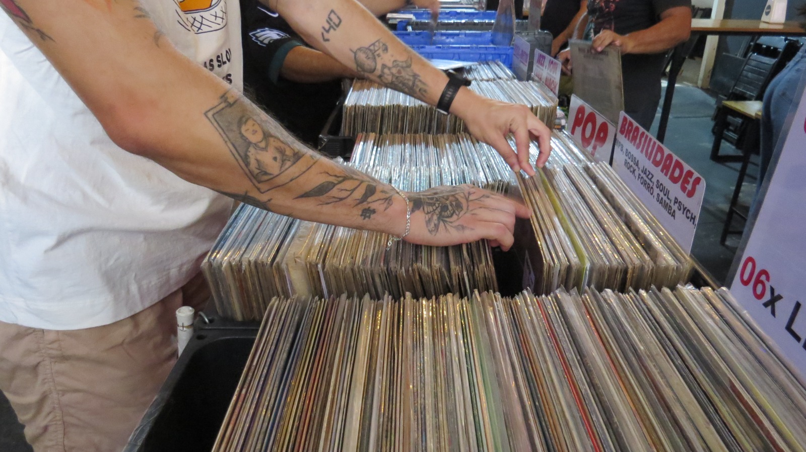 homem manuseando caixa com vinis ou PLs em feira de disco