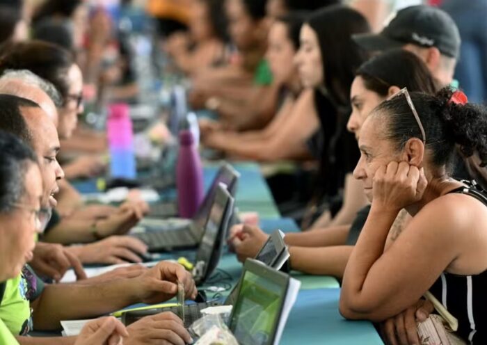 atendentes em laptos recebendo candidatos a empregos em Feira de empregabilidade