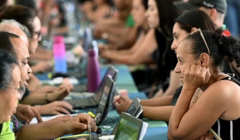 atendentes em laptos recebendo candidatos a empregos em Feira de empregabilidade