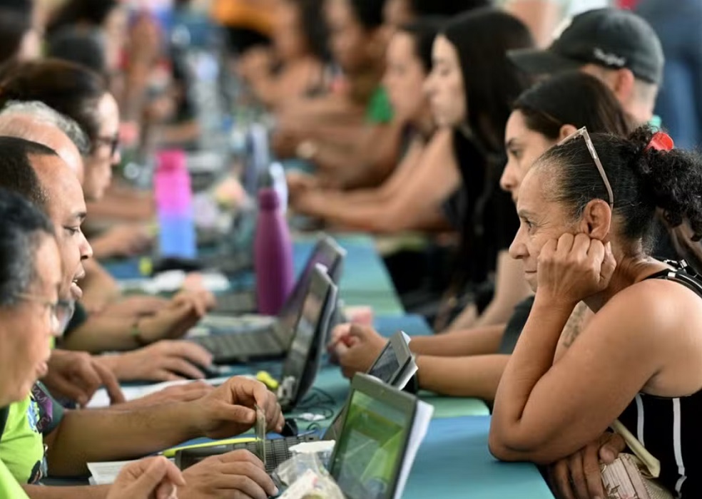 atendentes em laptos recebendo candidatos a empregos em Feira de empregabilidade