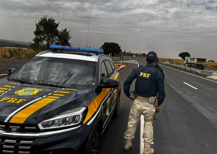 Agente da PRF ao lado de viatura às margens na via Dutra; Homem é preso por importunação sexual em ônibus na Dutra