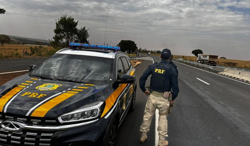 Agente da PRF ao lado de viatura às margens na via Dutra; Homem é preso por importunação sexual em ônibus na Dutra