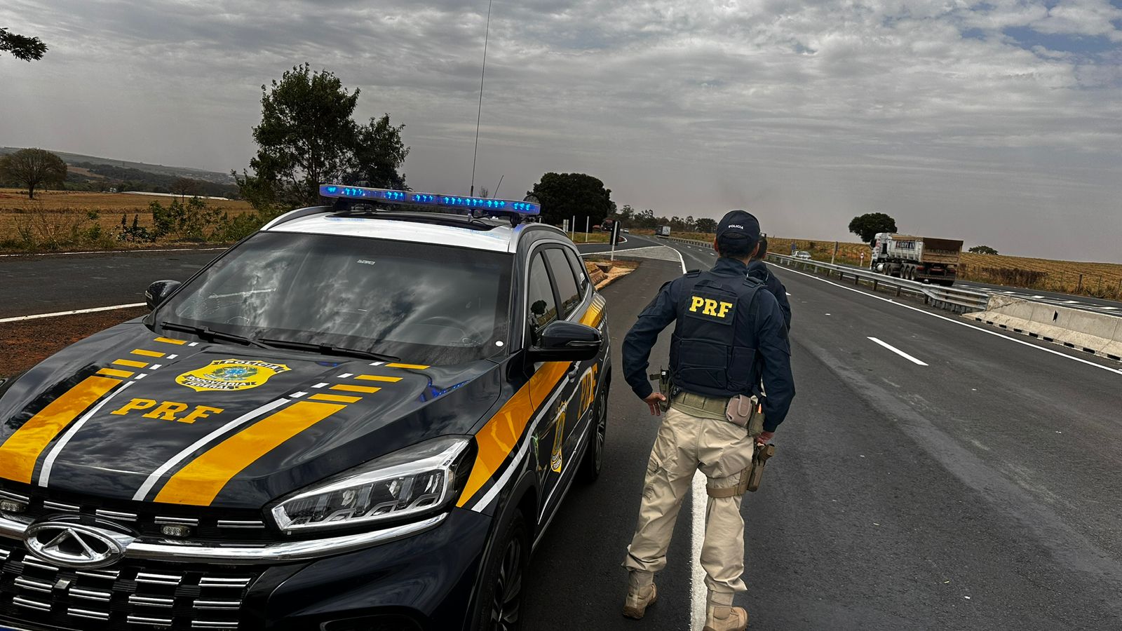 Agente da PRF ao lado de viatura às margens na via Dutra; Homem é preso por importunação sexual em ônibus na Dutra